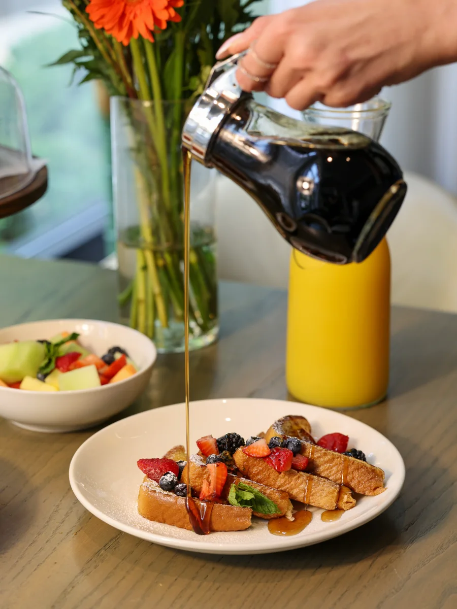 Syrup being poured over French toast and berries at Magnificent Mile